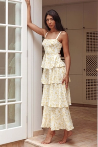 Detail of tiered yellow floral sundress showing layered skirt and delicate shoulder straps
