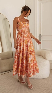 Detail of summer floral maxi dress featuring yellow orange tiered skirt and camisole top