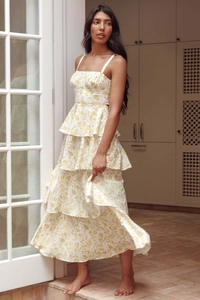 Detail shot of the yellow floral pattern on a tiered white summer dress with thin straps