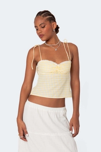 Detail of yellow gingham top featuring white lace trim and adjustable bow straps