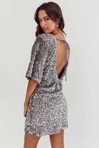 Detail of elegant sequined silver dress featuring a deep V-back and cross-tie straps