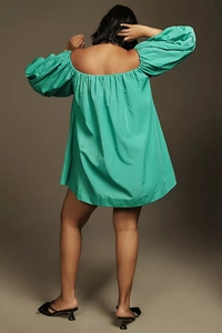 Detail view of emerald green off-shoulder puff sleeves and satin texture on back of dress