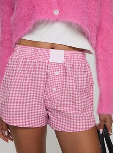 Detail of pink plaid high-waist summer shorts with elastic waistband and soft fabric