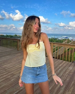 Detail of yellow gingham crop top with chest pleats and raw edge denim mini skirt