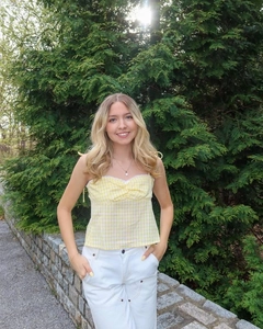 Detail of yellow gingham crop top featuring lace trim and adjustable tie shoulder straps