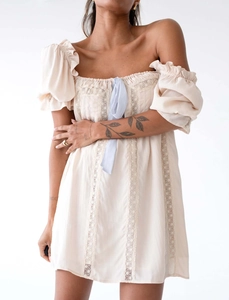 Détail de la robe crème à épaules dénudées avec dentelle et petit nœud ruban bleu