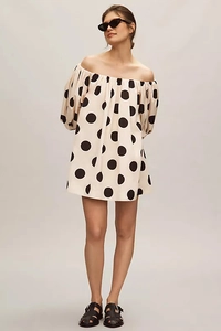 Detail of off-shoulder puff sleeves and large black polka dots on apricot dress