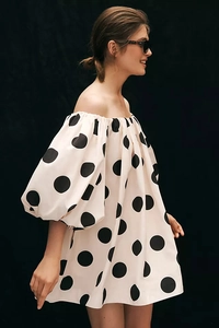 Detailed side view of off-white off-shoulder dress with black polka dots and puff sleeves