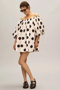 Detail of off-shoulder bubble sleeve dress with black polka dots on cream fabric