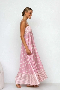 Side view of silky pink satin maxi dress with white polka dots and striped hem details