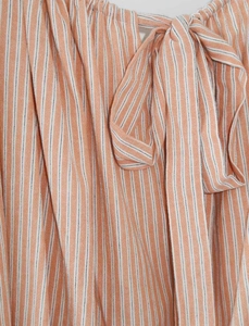 Detalle de vestido de manga abullonada a rayas con líneas naranjas y cuello de lazo