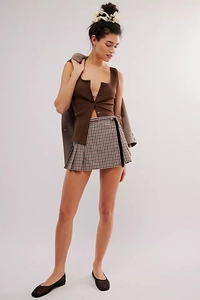 Detail of dark brown ribbed knit vest featuring front buttons and vintage style plaid skirt