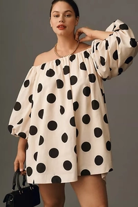 Detail of off-shoulder cream dress with large black polka dots and stylish puff sleeves