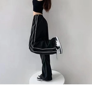 Detail of black wide-leg trousers with side stripes and elastic drawstring waist