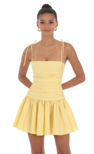 Détail du corsage froncé et des fines bretelles sur une robe courte jaune clair
