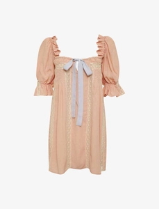 Détail de la robe mini rose pêche avec bordure en dentelle blanche et nœud ruban bleu