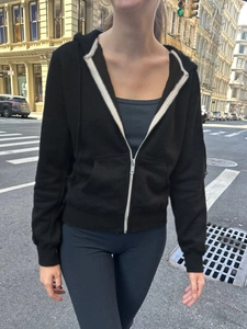 Close-up of black zip-up hoodie featuring white stripe trim and urban street style design