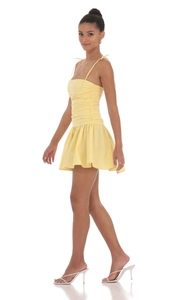 Détail de mini robe jaune clair avec bustier froncé et jupe évasée pour l'été