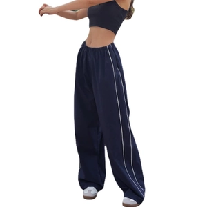 Detail of loose fit dark blue track pants with white side stripes and elastic waist