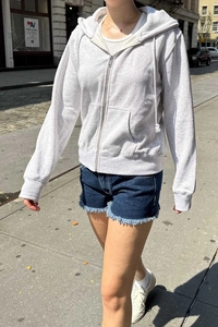 Detail of light grey zip-up hoodie featuring adjustable drawstring and front pockets