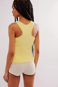 Detail of light yellow ribbed knit tank top with delicate wavy scalloped lace edges