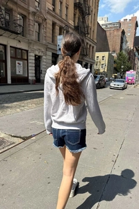 Outdoor back view of a grey zip-up hoodie and frayed denim shorts for women's casual style