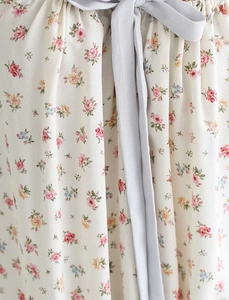 Detalle de vestido floral con cordón de gasa gris claro y una textura de tela plisada