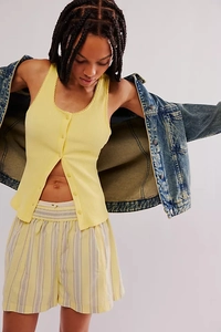 Detail of a light yellow ribbed knit tank top with delicate scalloped lace edges and buttons