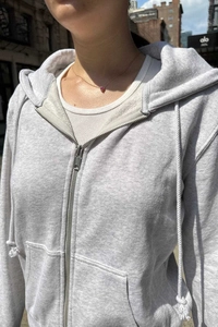 Detail of light gray zip-up hoodie featuring silver metal zipper and soft cotton texture