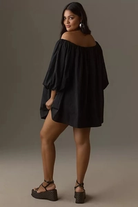Detail of off-shoulder puff sleeves on a loose black mini dress for fashion styling