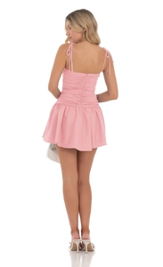 Détail de la robe mini rose avec fines bretelles réglables et ourlet à volants élégants