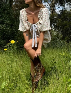 Vestido babydoll vintage de flores con mangas abullonadas y lazo azul en el campo