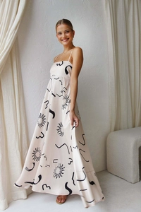 Detail of satin maxi dress with thin straps and black abstract sun pattern on apricot