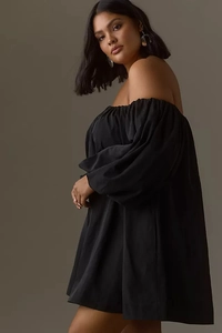 Detail of off-shoulder black dress featuring puff long sleeves and elegant woven texture