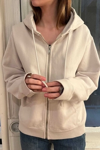 Detailed shot of beige zip-up hoodie featuring adjustable drawstring and metal zipper