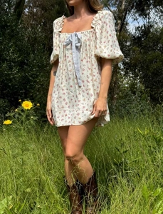 Detalle de vestido floral con mangas abullonadas, escote cuadrado y lazo azul