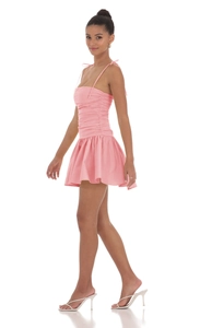 Vue latérale de la mini robe rose froncée avec bretelles à nœuds et jupe plissée