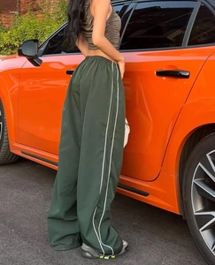 Detail view of dark green wide leg track pants with white double side stripes and elastic waist