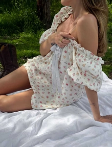 Detalle del vestido floral con hombros descubiertos, lazo azul y escote de volantes