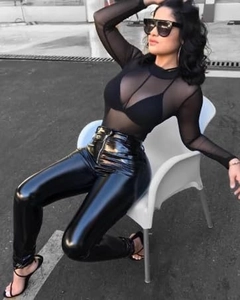 Detail of sheer mesh long sleeve top paired with high-waisted black faux leather leggings
