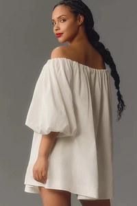 Detailed view of elastic off-shoulder neckline and dramatic puff sleeves on white dress