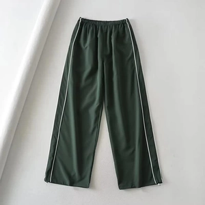 Detail of adjustable white drawstring on the hem of dark green wide-leg trousers