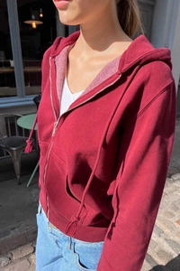 Detail of burgundy zip-up hoodie with drawstring hood and metal zipper in outdoor light
