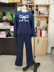 Détail d'un ensemble détente bleu marine avec broderie nœud blanc et manches longues amples