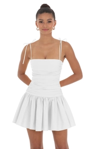 Détail de la robe mini blanche avec bretelles nouées et corsage froncé pour l'été