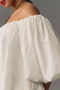 Close-up of the elegant white off-shoulder dress featuring voluminous puff sleeves
