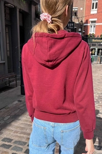 Detailed shot of ribbed cuffs and hem on a maroon zip-up hoodie for a casual vintage look