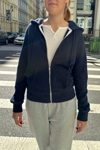 Detail of navy zip-up hoodie with drawstring hood and kangaroo pockets in street setting