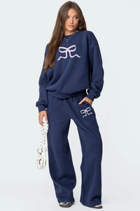 Détail d'ensemble sweat bleu marine avec nœud rose et pantalon large de détente