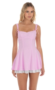 Détail de robe mini rose avec fines bretelles et dentelle plissée blanche en bas